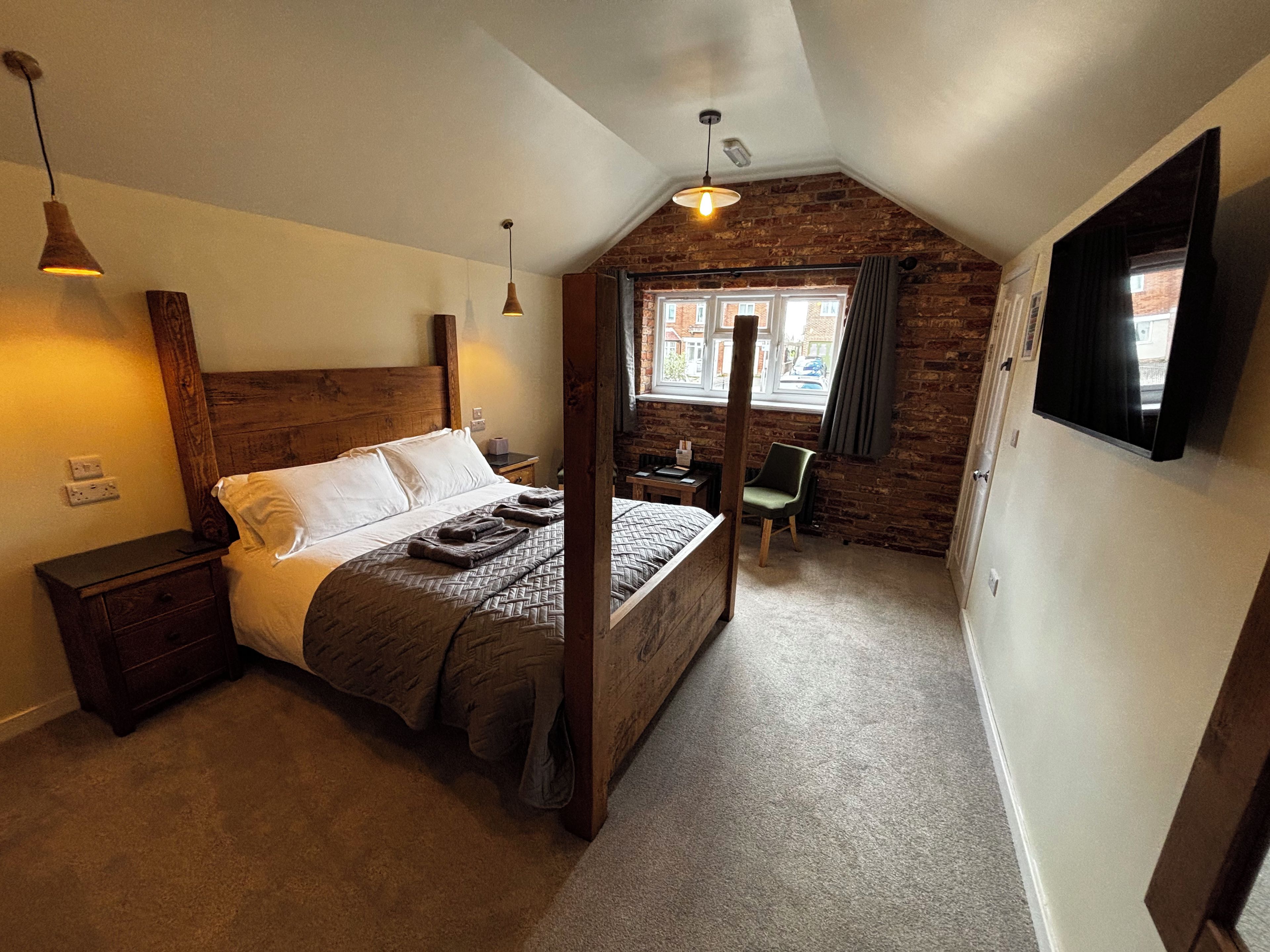 Un dormitorio con cama con dosel, un escritorio, una silla y una ventana con cortinas.