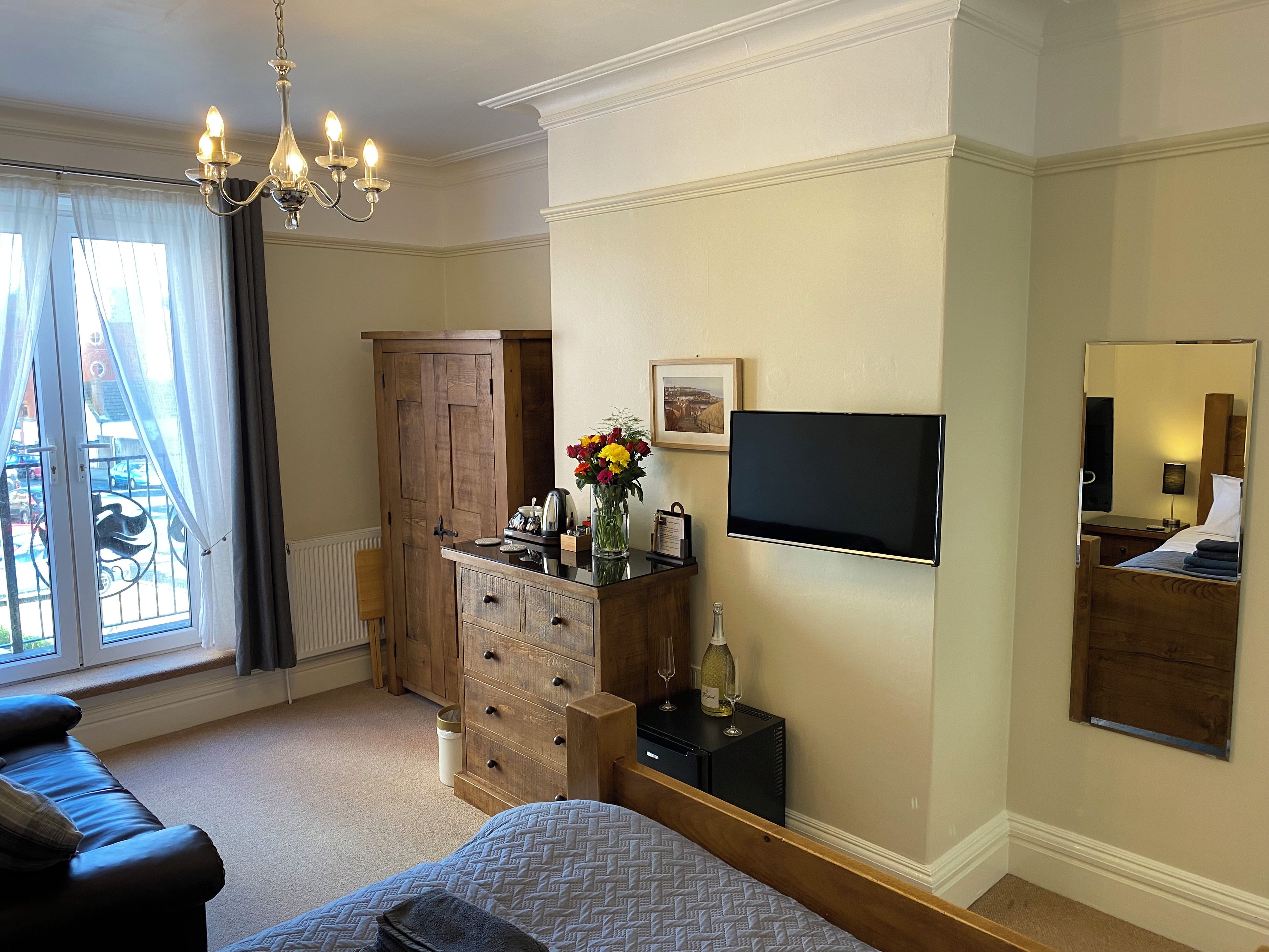 A hotel room with a bed, a dresser, a television, and a window with curtains.