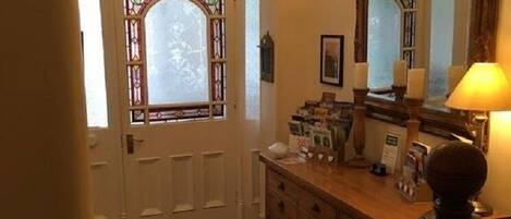 A room with a herringbone patterned floor, a wooden cabinet with a mirror, and a chandelier.