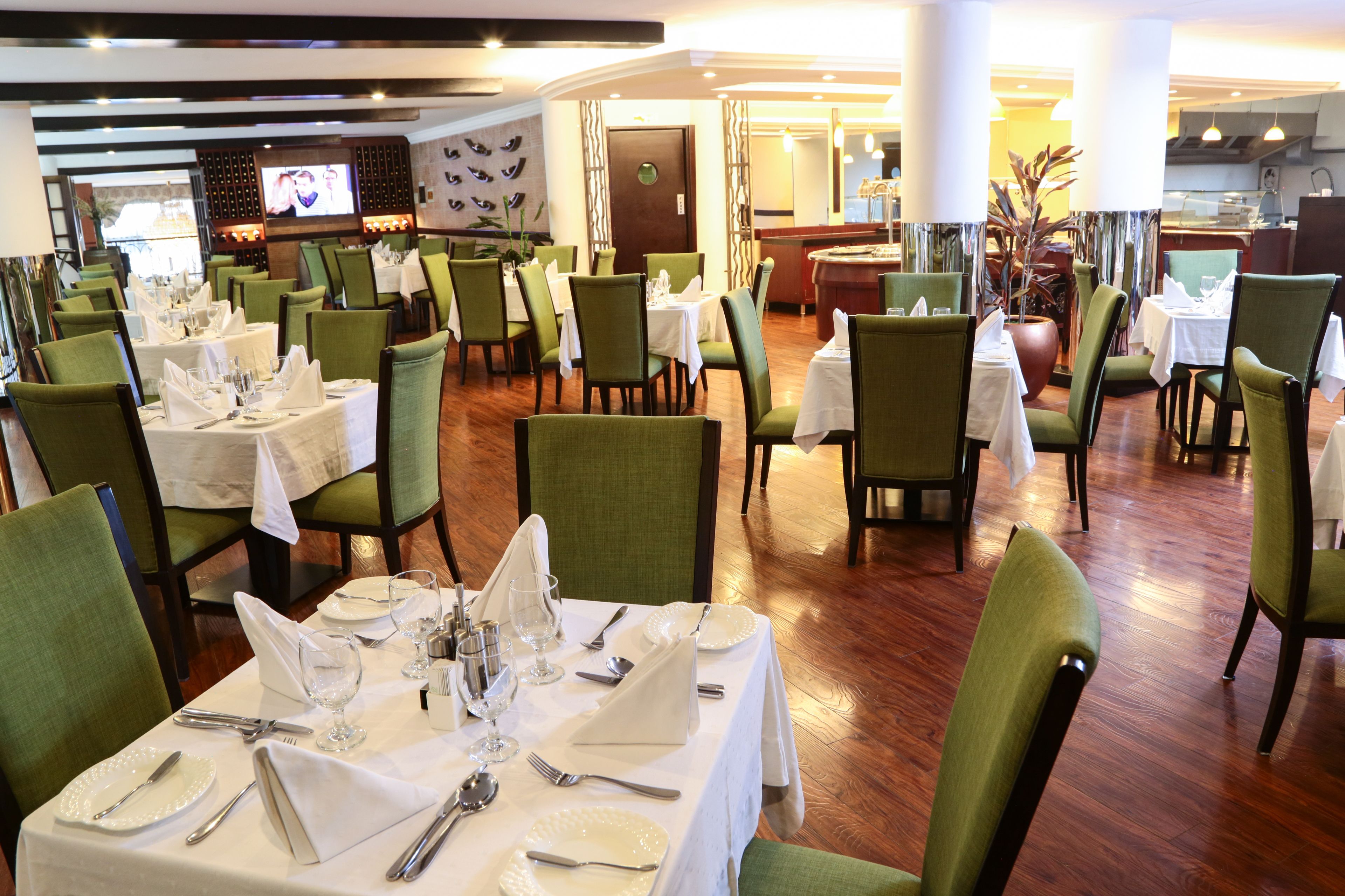A restaurant with multiple tables set for dining, each with chairs and neatly arranged table settings.