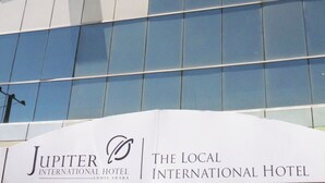 Un edificio moderno con ventanas de vidrio reflectante y un cartel para el Hotel Jupiter International.
