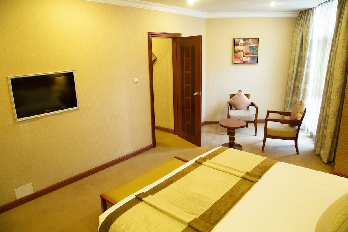 Une chambre d’hôtel avec un lit, un téléviseur fixé au mur, une petite table et une chaise.