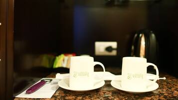 A kitchen counter with two white cups and a saucer, a purple pen, and a document.