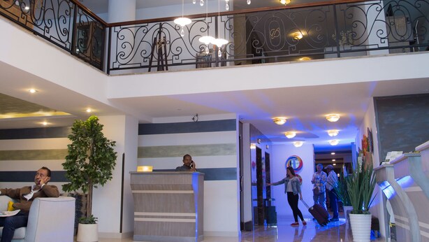 Un hall espacioso con techo alto, un mostrador de recepción y una escalera que conduce a un nivel superior.