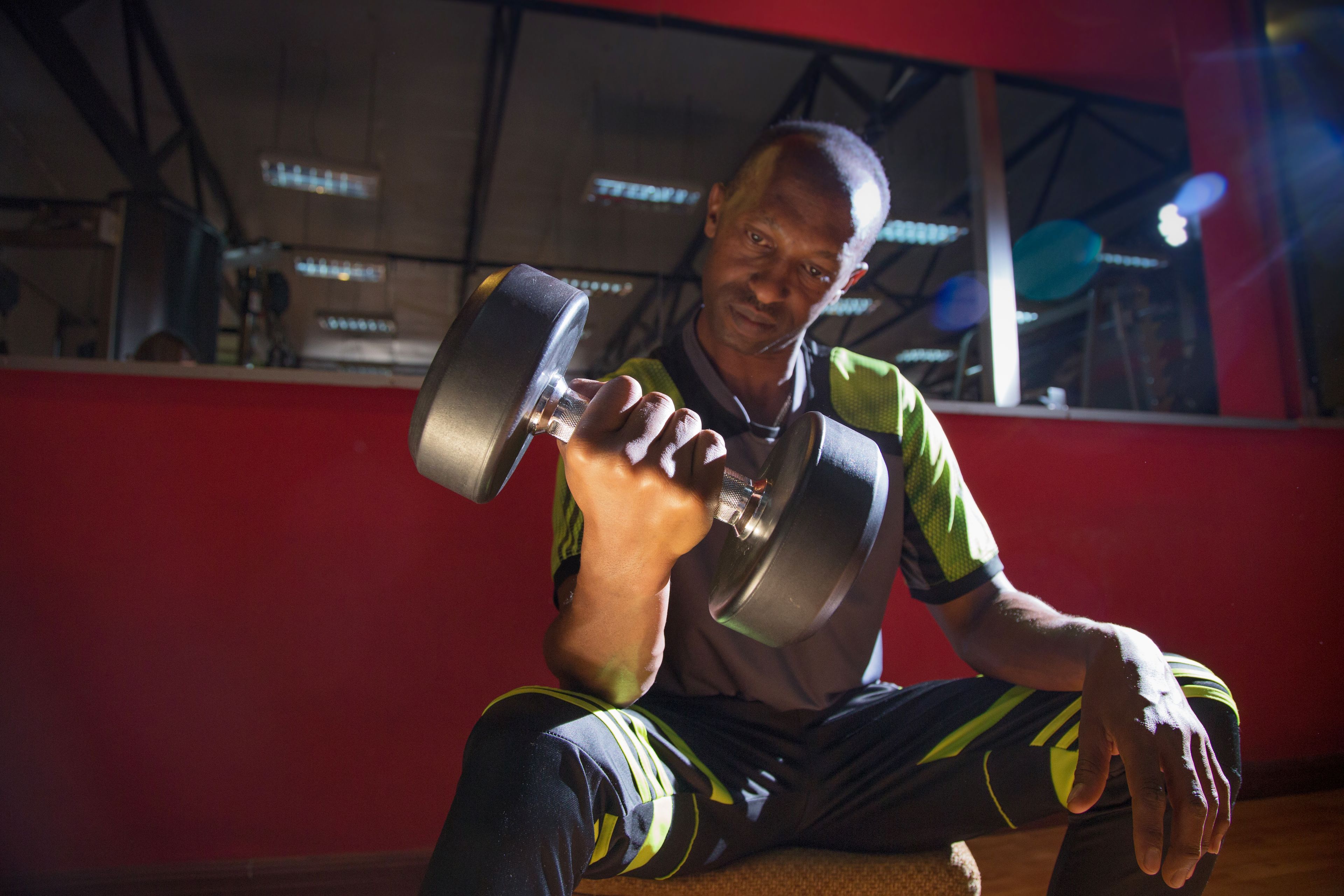 A person sitting on a bench, holding a dumbbell.