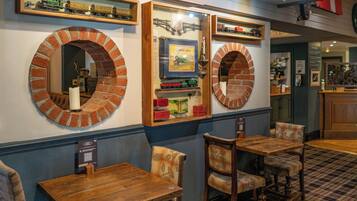 A restaurant interior with brick arch mirrors, wooden tables, and chairs.
