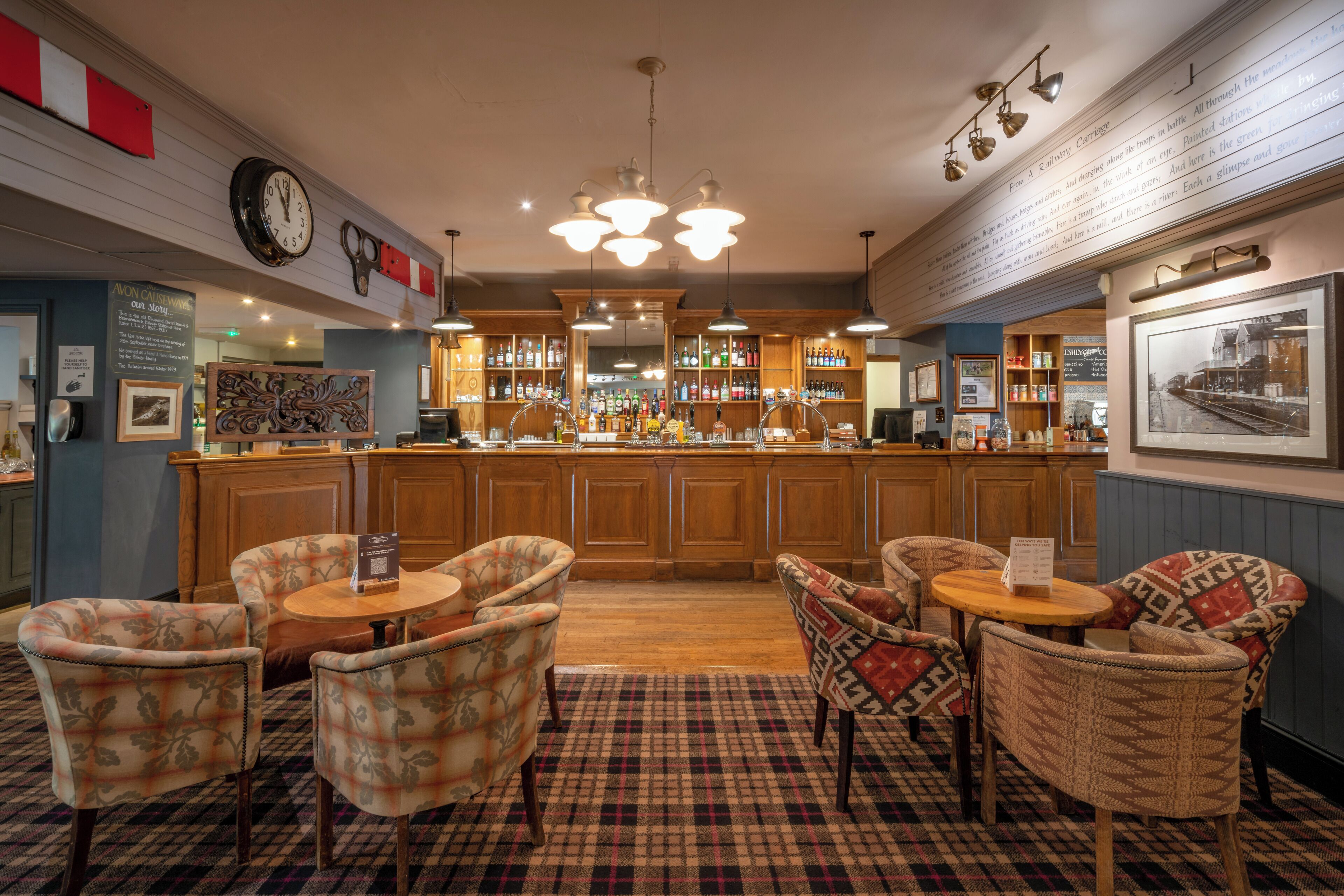 A bar area with wooden cabinets, a clock, and patterned chairs.