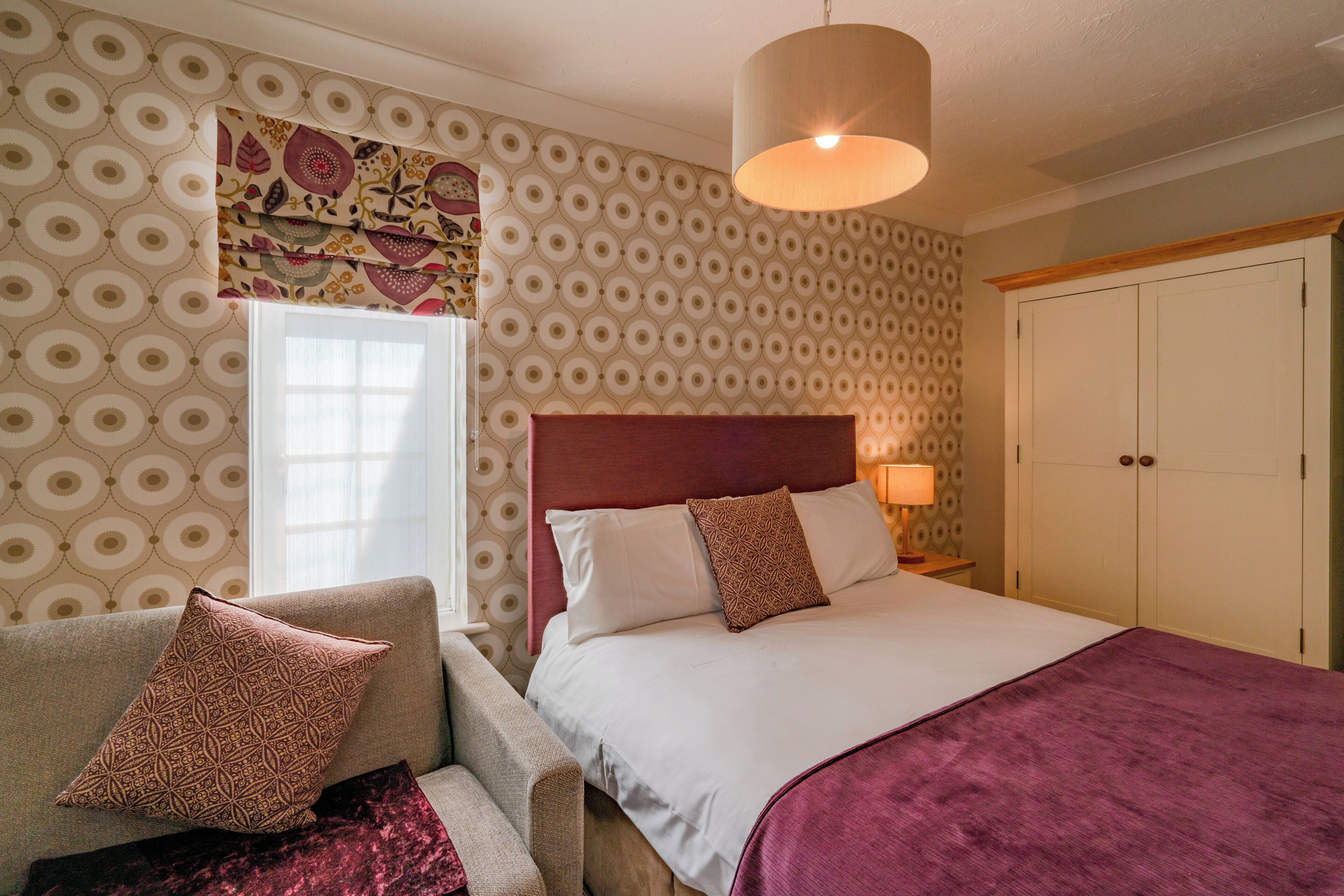 A bedroom with a bed, a nightstand, a chair, and a wardrobe.