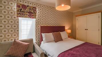 A bedroom with a bed, a nightstand, a chair, and a wardrobe.