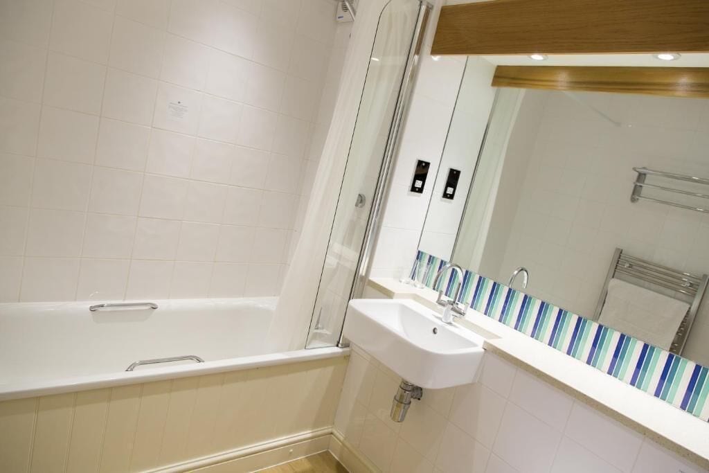 A modern bathroom with a bathtub, a sink, and a mirror.