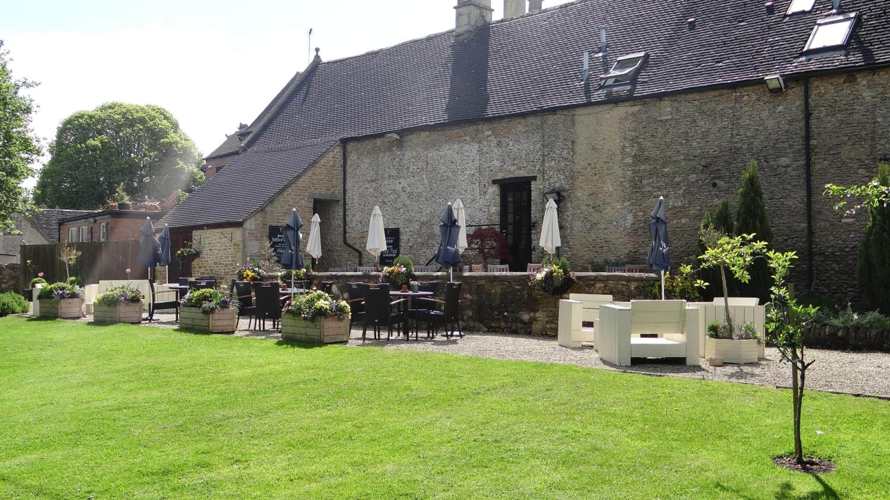 A stone building with outdoor seating and planters.