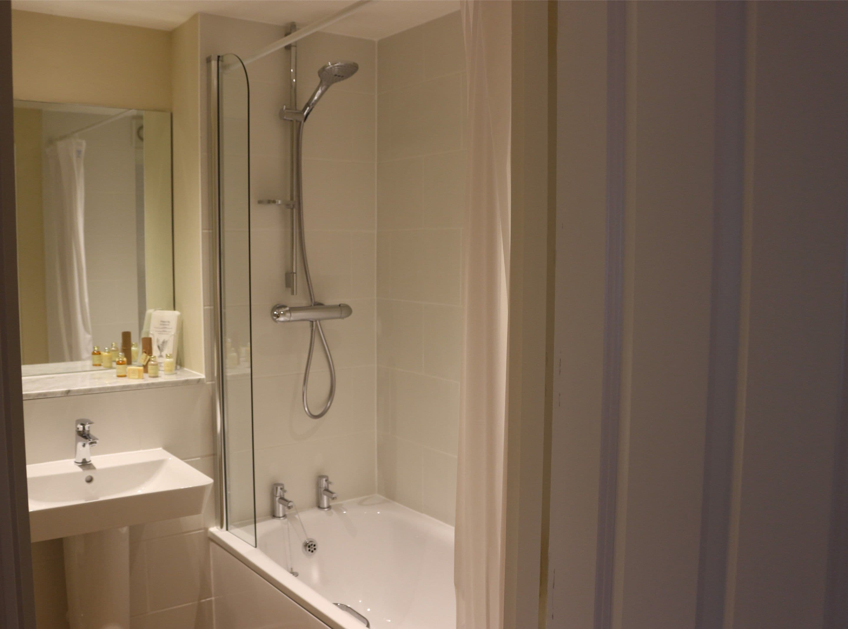 A modern bathroom with a glass-enclosed shower, a white sink, and a bathtub.