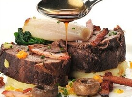 Un plato con un guiso de carne, verduras y salsa que se está sirviendo.