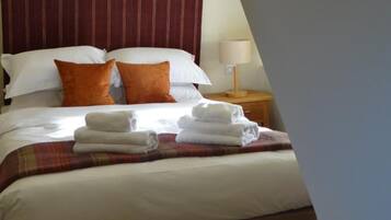 Una habitació d'hotel amb un llit gran, un panell de capçalera a ratlles i una tauleta de nit amb una làmpada.