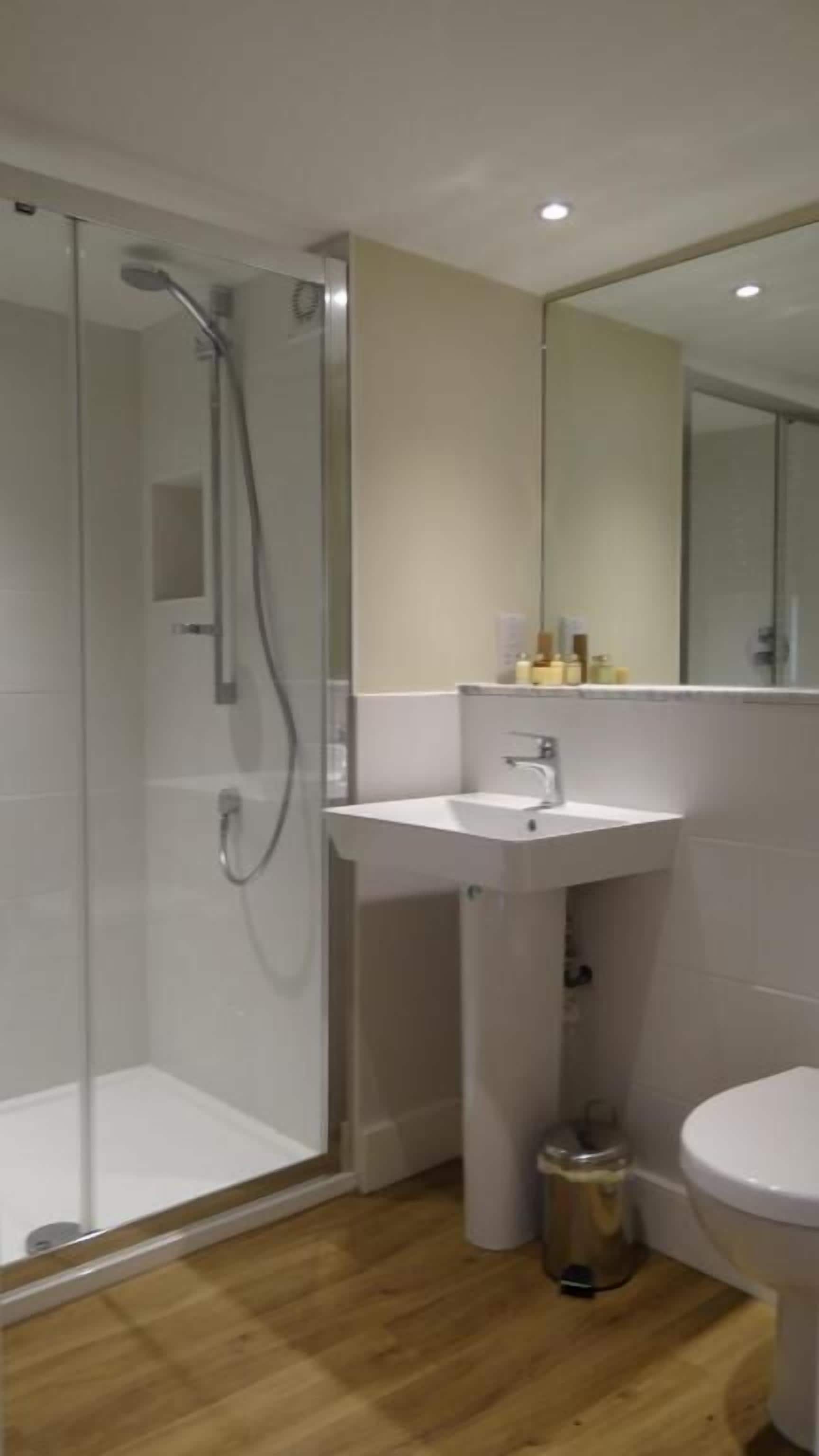 Ein modernes Badezimmer mit einer Duschkabine, einem Waschbecken auf Säule und einer Toilette.