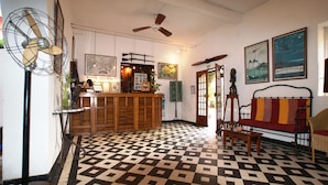A lobby with a check-in counter, a ceiling fan, a patterned floor, and a sofa. - Hotel La Residence (St. Louis)