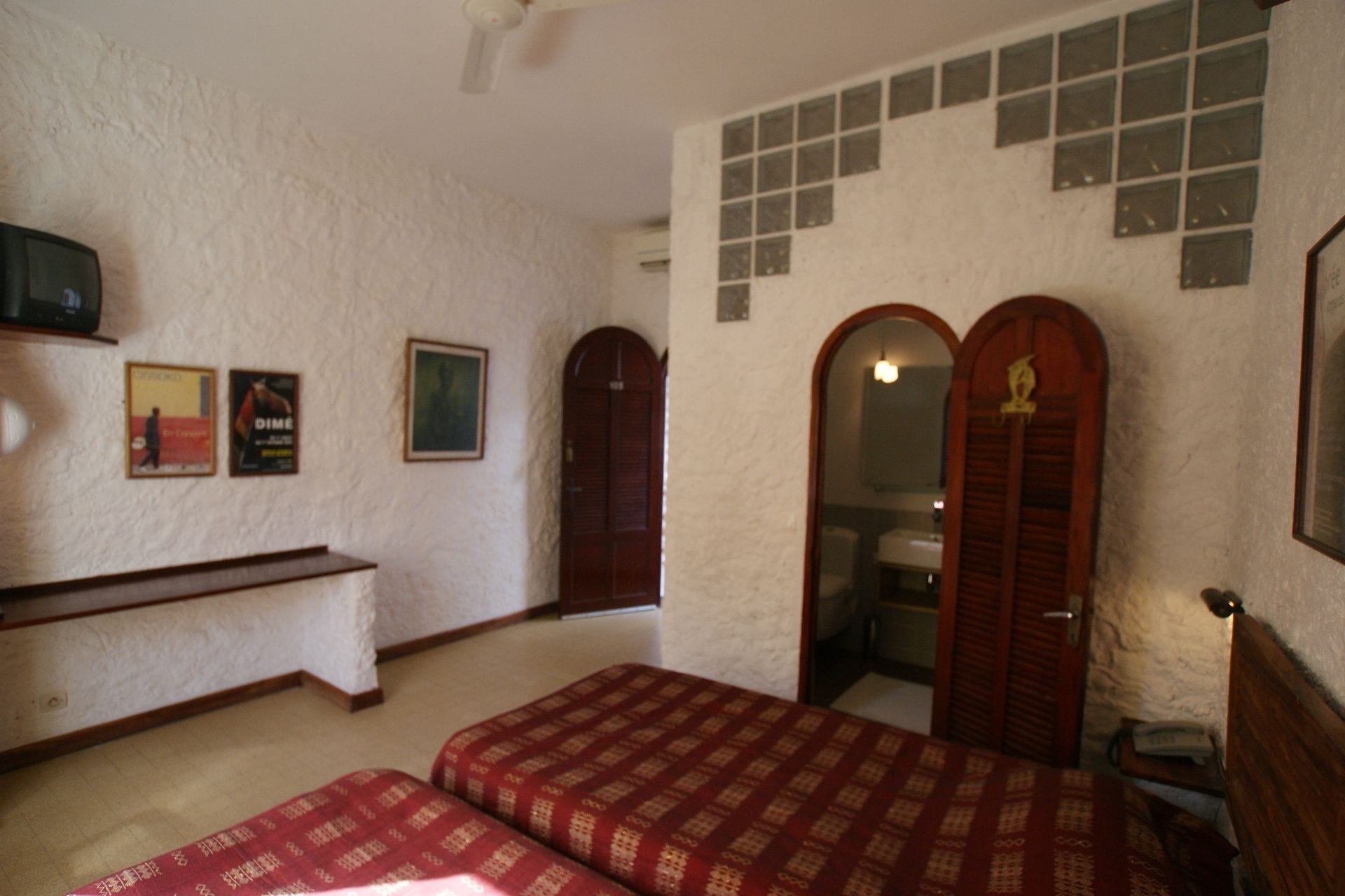 A bedroom with two beds, a wooden bench, a small table, and a mirror.