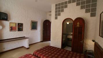 A bedroom with two beds, a wooden bench, a small table, and a mirror.