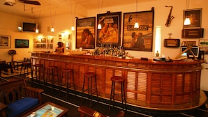 A bar area with wooden stools, a bar counter, and posters on the wall. - Hotel La Residence (St. Louis)