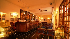 A bar area with wooden furniture, a counter, and a ceiling fan. - Hotel La Residence (St. Louis)