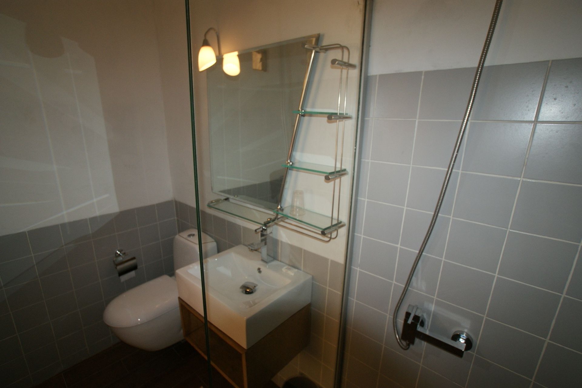 A bathroom with a glass shower enclosure, a toilet, and a sink with a mirror above it.
