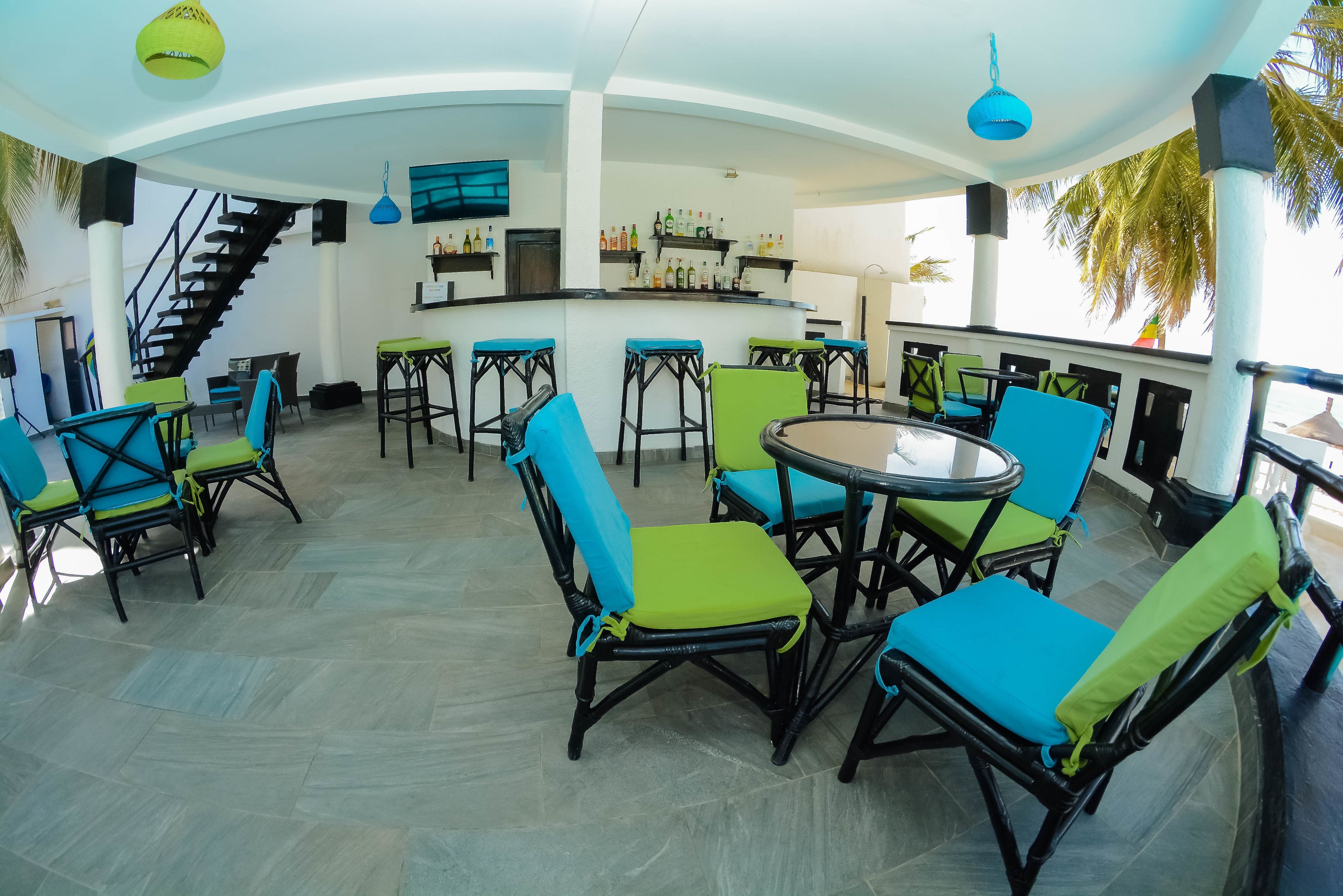 A spacious indoor area with a bar, multiple seating arrangements, and a staircase leading to an upper level.