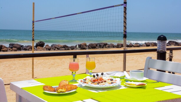 Una mesa con alimentos y bebidas para el desayuno, frente a la playa y con vistas al océano.