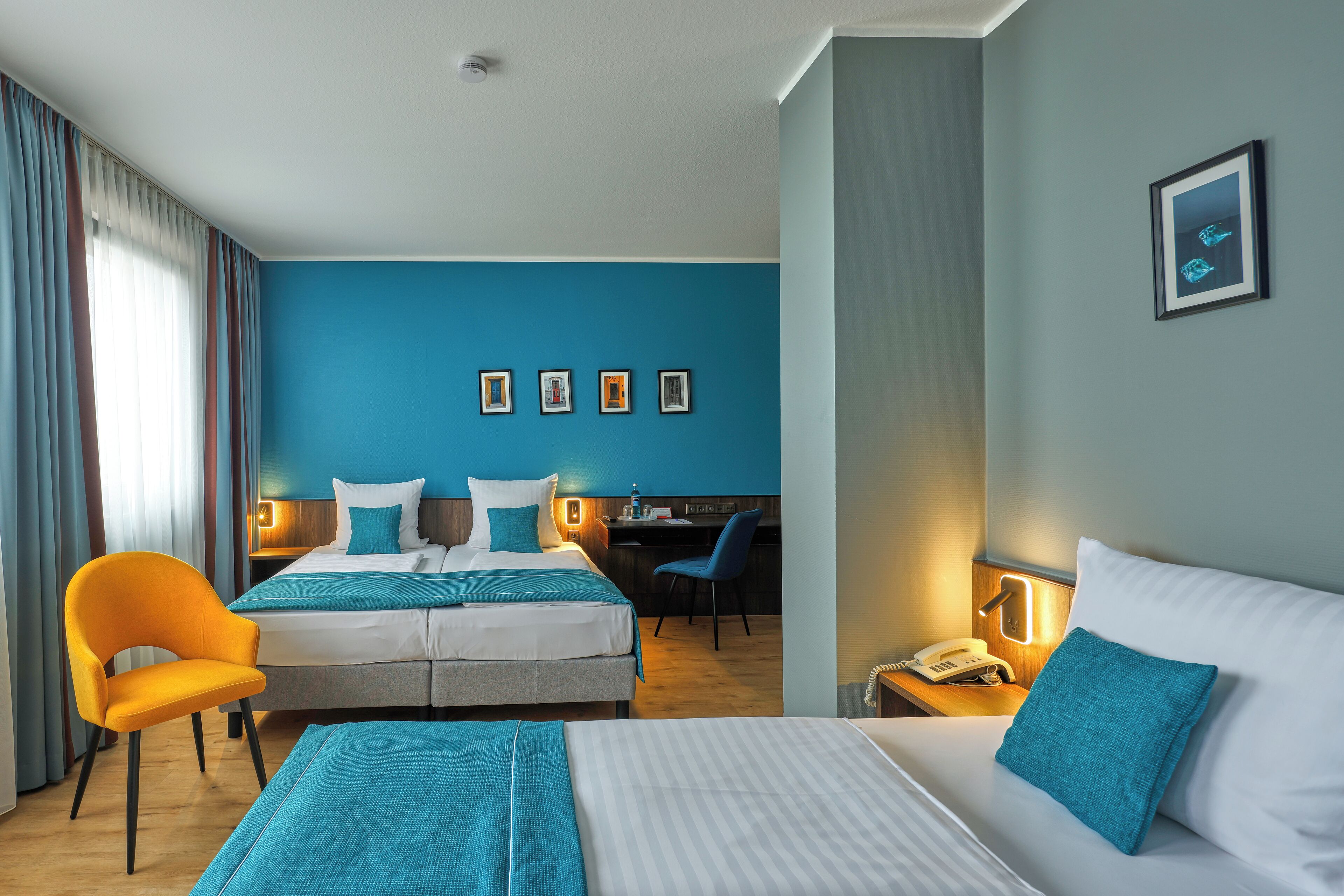 Een hotelkamer met een groot bed, een bureau, een stoel en een nachtkastje met een telefoon.