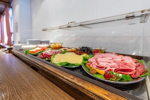 Un bufé con diversas opciones de comida, incluyendo carnes, quesos y verduras.