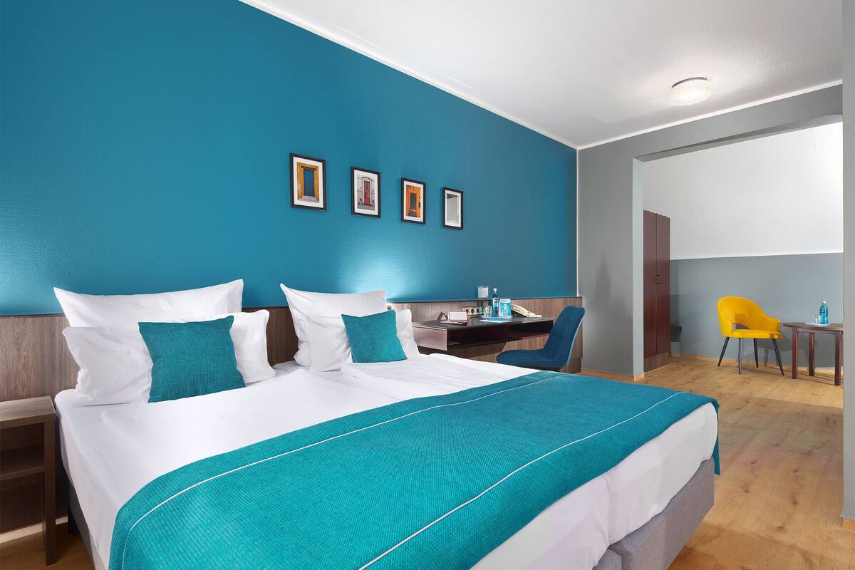 Een hotelkamer met een bed, een bureau, een stoel en een klein tafeltje.