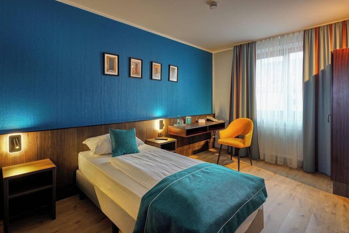 Een hotelkamer met een bed, een bureau, een stoel en een raam met gordijnen.