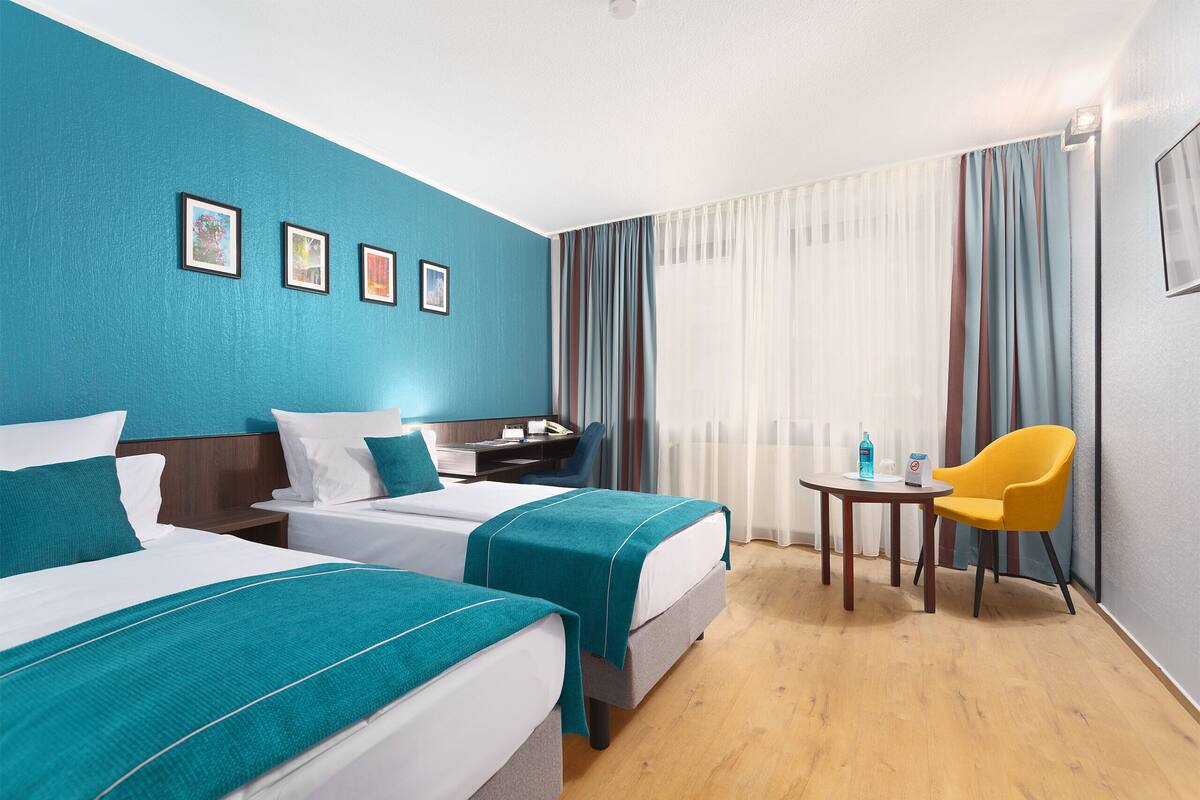 Een hotelkamer met twee bedden, een bureau, een stoel en een klein tafeltje.