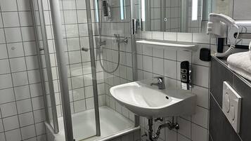 A bathroom with a glass-enclosed shower, a sink, and a toilet.