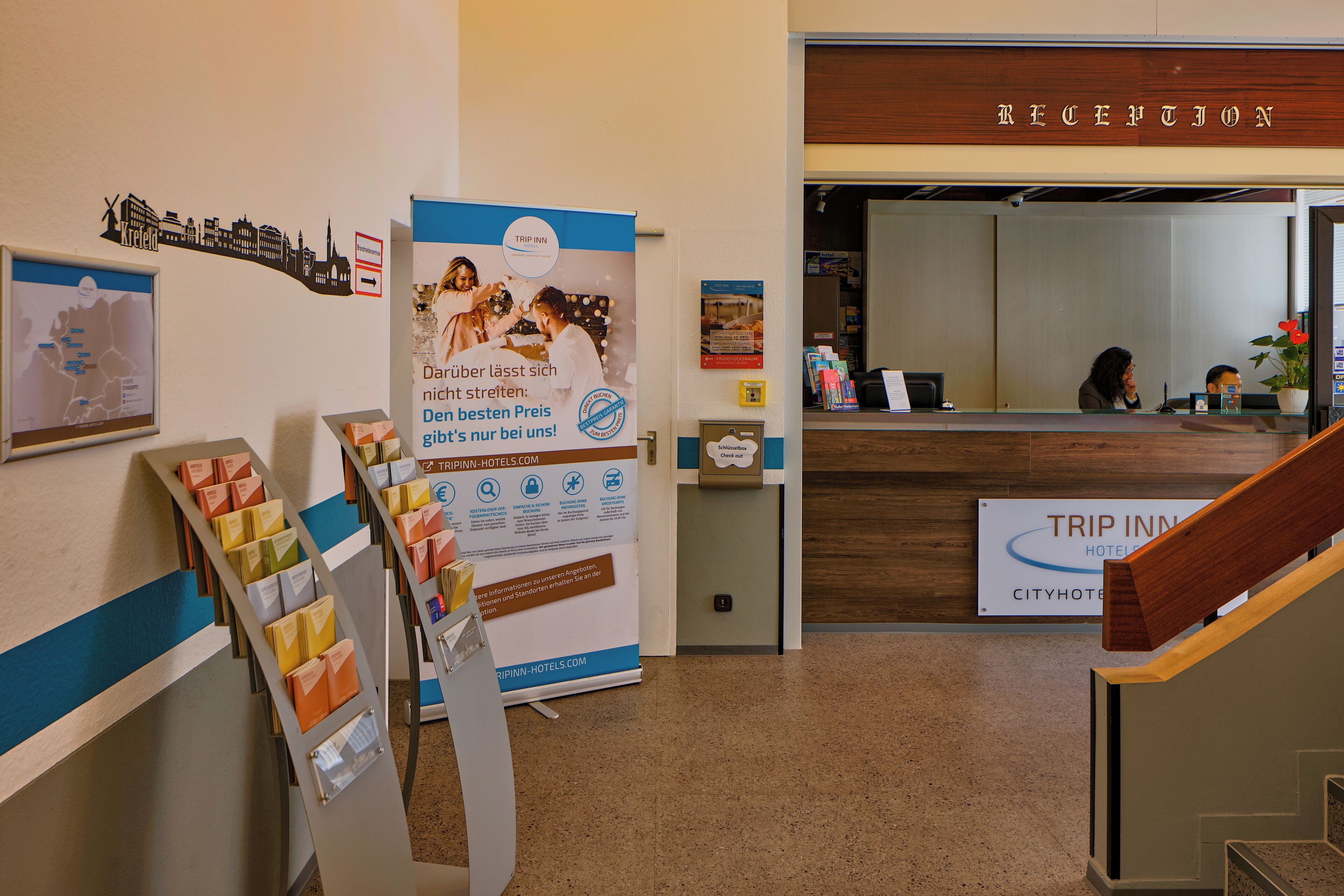 A reception area with a wooden reception desk, a sign reading "RECEPTION", and a staircase leading to an upper floor.