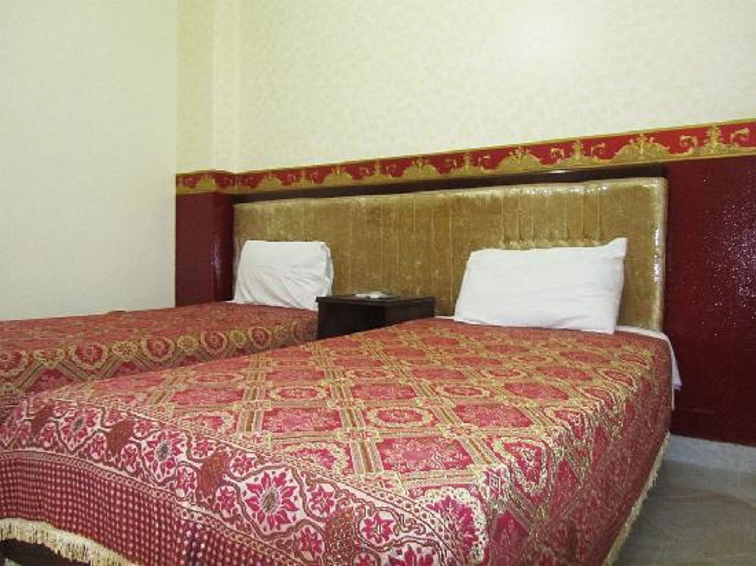 A hotel room with a large bed, a headboard with a decorative pattern, and a nightstand.