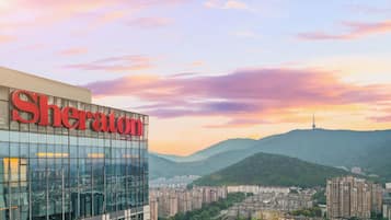 Experience the vibrant city atmosphere at Sheraton Hotel, set amidst lush green hills and urban landscapes.