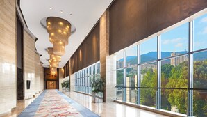 A spacious corridor with a patterned carpet, large windows offering a city view, and a modern chandelier. - Sheraton Wuxi Binhu Hotel (Wuxi)