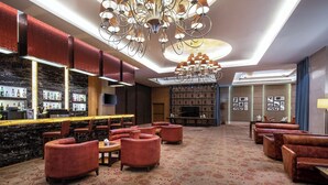 A spacious lobby with a bar area, leather seating, a large chandelier, and a television screen. - Sheraton Wuxi Binhu Hotel (Wuxi)