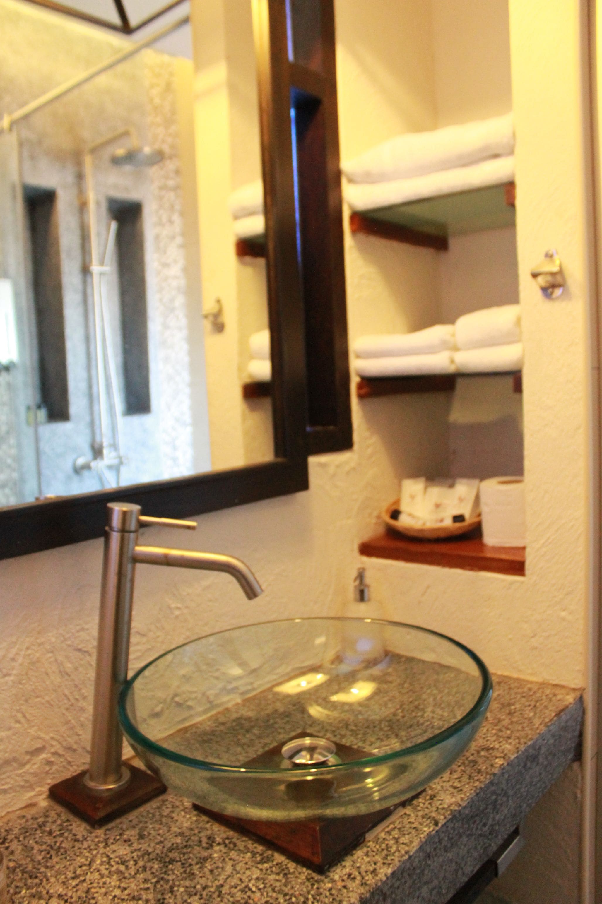 A bathroom with a glass bowl sink, a towel rack, and a mirror.
