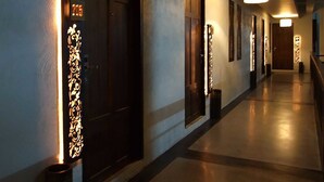 Un pasillo con puertas, iluminado por apliques y una lámpara de techo.