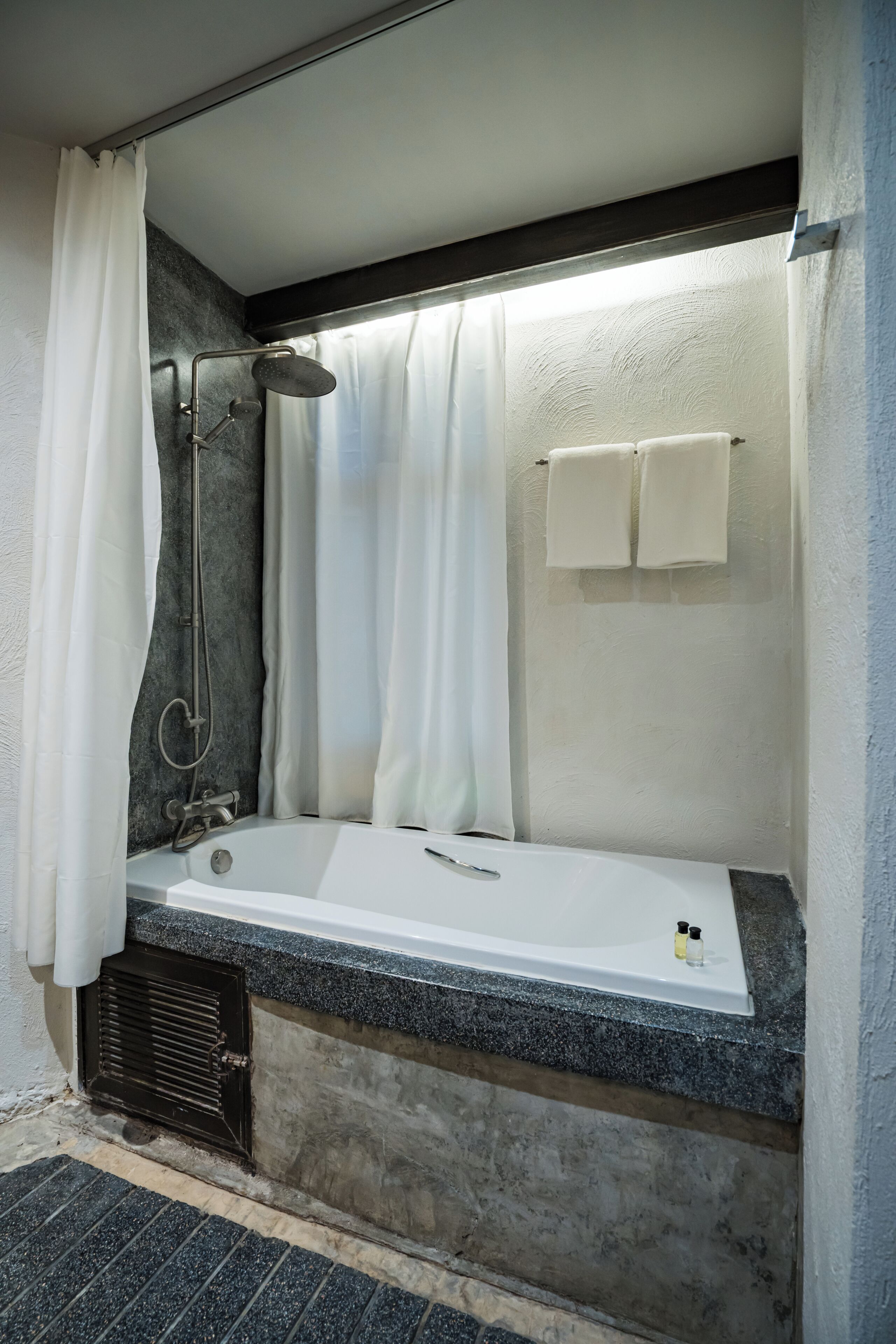A modern bathroom with a bathtub, shower, and towel rack.