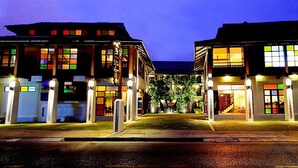 Un hotel de estilo arquitectónico moderno, con un patio central con vegetación y una entrada bien iluminada.