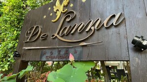 Un letrero de madera del Hotel De Lanna con un emblema dorado decorativo y la inscripción 'HOTEL CHIANGMA'.