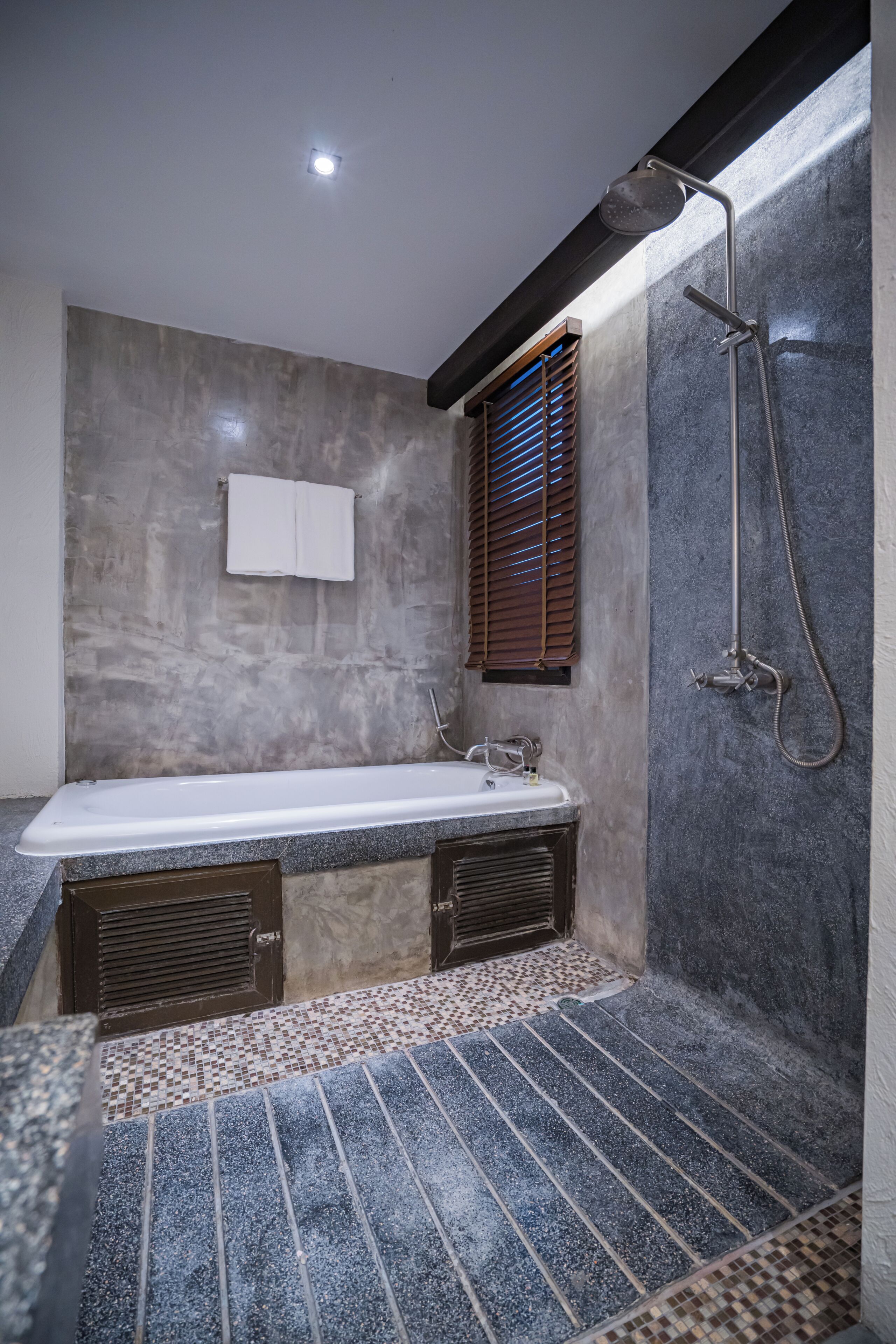 Une salle de bain avec une baignoire, une douche et un carrelage au sol.