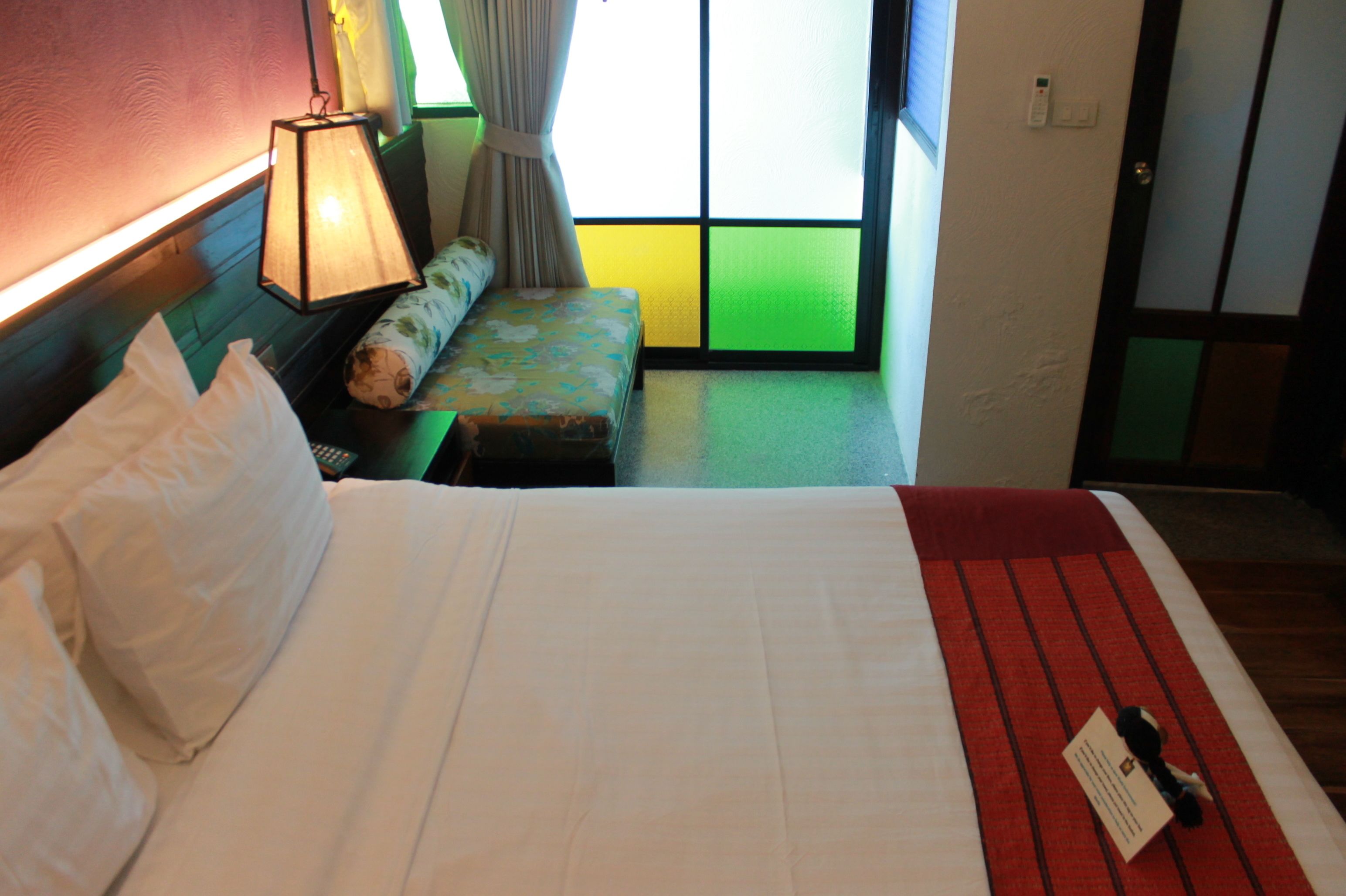 A hotel room with a bed, a bedside lamp, a bench, and a window with a view.