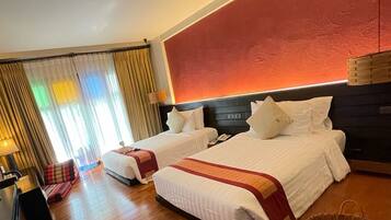 Habitación de hotel con dos camas, un escritorio, una silla y un amplio ventanal con cortinas.