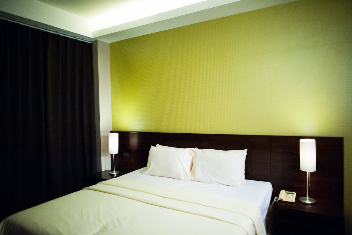Una habitación de hotel con una cama grande, dos lámparas de noche y un teléfono en la mesita de noche.