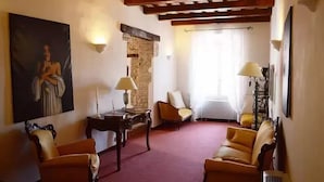 A room with a stone wall, a large painting, two chairs, a table, and a bed with a window. - Hotel Della Fonte (Greccio)
