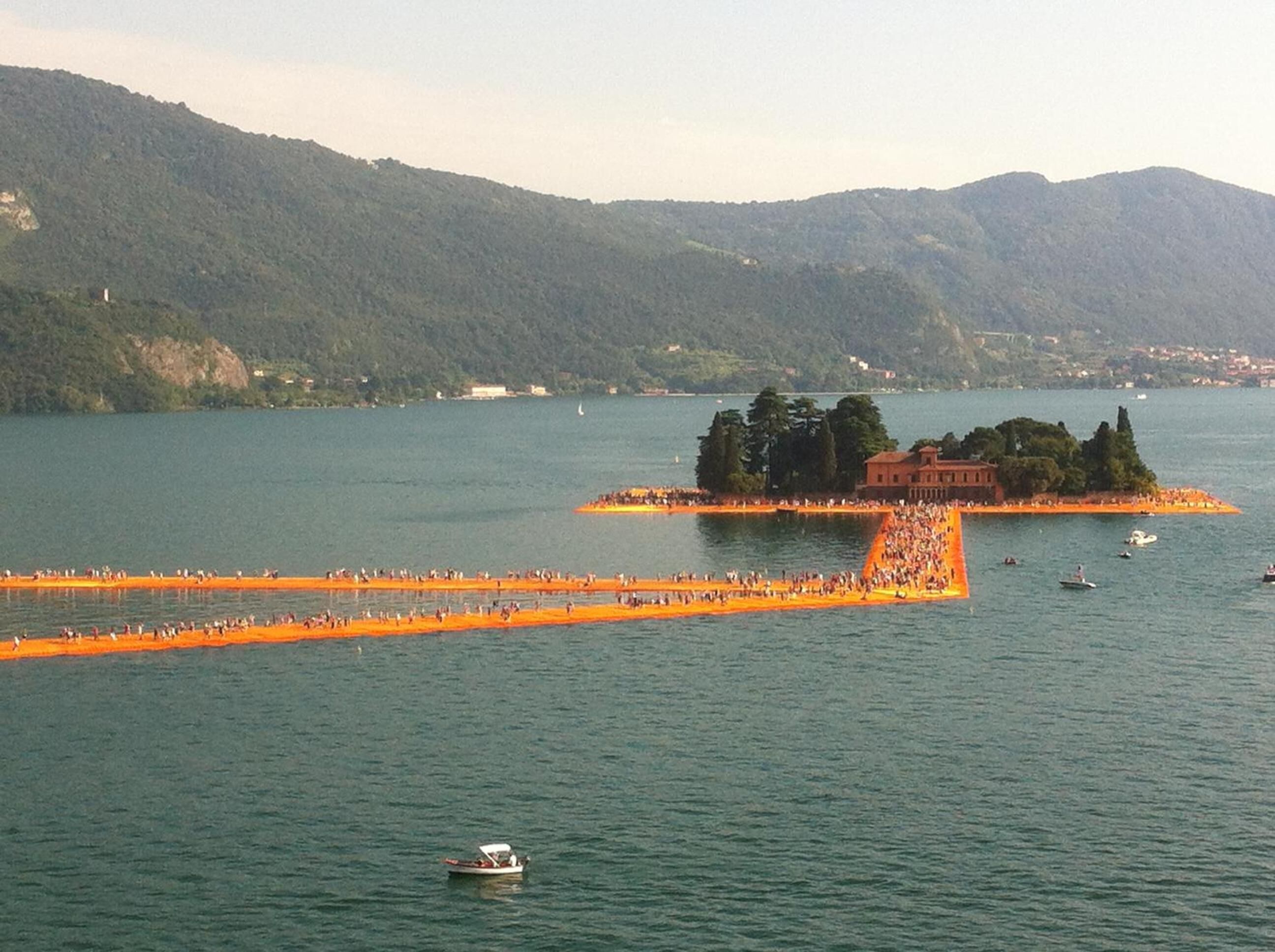 Ein See mit einer kleinen Insel und einer langen, orangefarbenen Mole, die ins Wasser ragt.