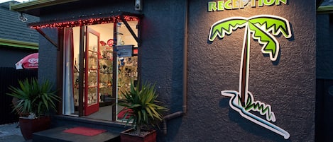A reception area with a palm tree sign, steps leading up to the entrance, and potted plants.